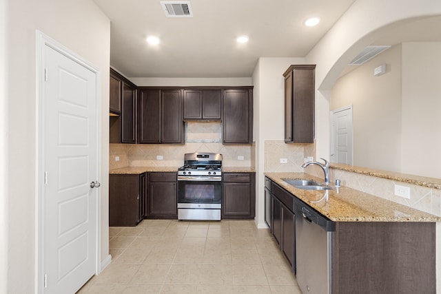 kitchen featuring light stone countertops, sink, stainless steel appliances, dark brown cabinets, and light tile patterned flooring