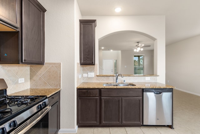 kitchen with light stone countertops, dark brown cabinets, stainless steel appliances, and sink