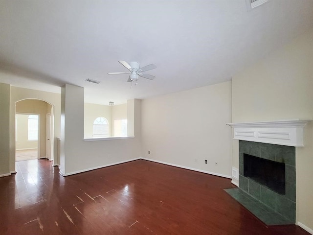 unfurnished living room featuring a tiled fireplace, ceiling fan, and dark hardwood / wood-style floors