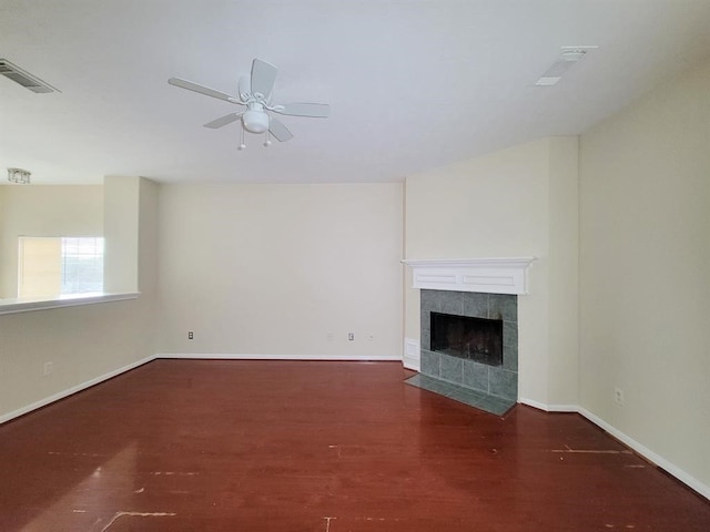 unfurnished living room featuring dark hardwood / wood-style floors, ceiling fan, and a tiled fireplace