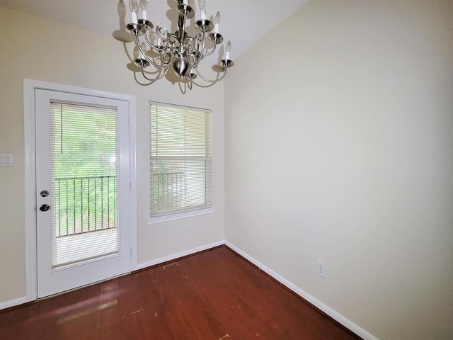 doorway to outside with dark hardwood / wood-style flooring, an inviting chandelier, and vaulted ceiling