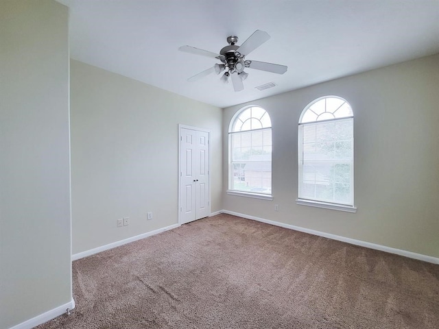 unfurnished room with ceiling fan and carpet