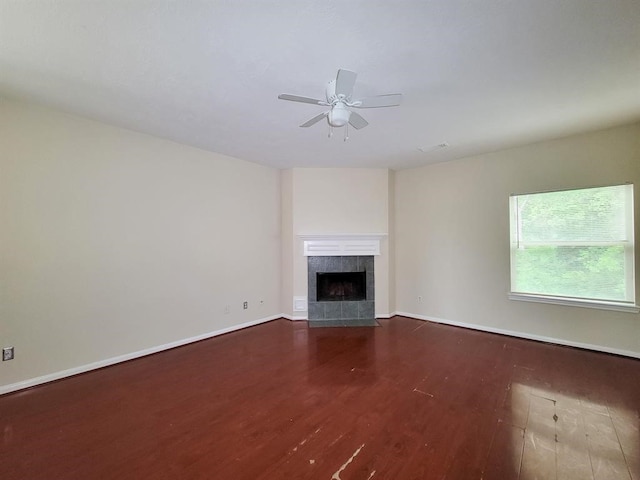 unfurnished living room with dark hardwood / wood-style floors, ceiling fan, and a tiled fireplace