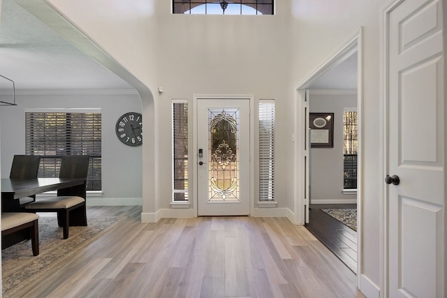 entrance foyer featuring a high ceiling, light wood-type flooring, and ornamental molding