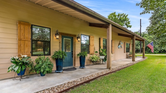 doorway to property with covered porch and a yard