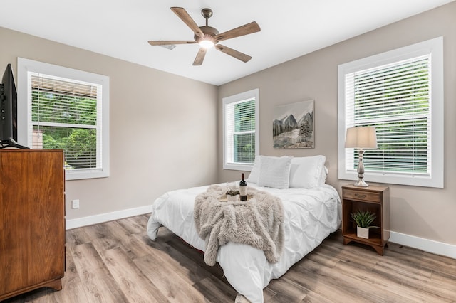 bedroom with multiple windows, ceiling fan, and hardwood / wood-style floors