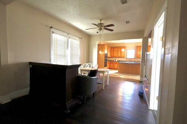 kitchen featuring black double oven, hanging light fixtures, a textured ceiling, dark hardwood / wood-style flooring, and ceiling fan