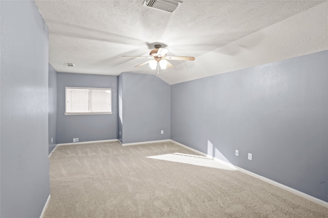 empty room with a textured ceiling, light colored carpet, ceiling fan, and lofted ceiling