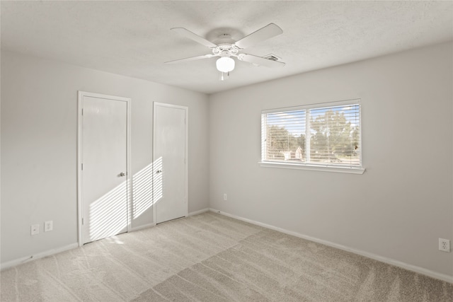 carpeted spare room with a textured ceiling and ceiling fan