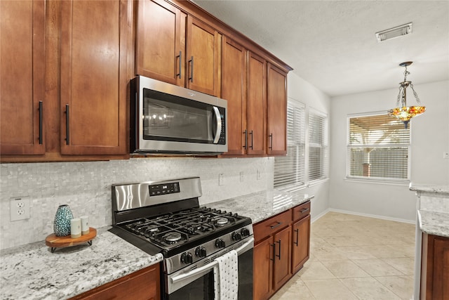 kitchen featuring decorative backsplash, light stone counters, light tile patterned floors, and appliances with stainless steel finishes