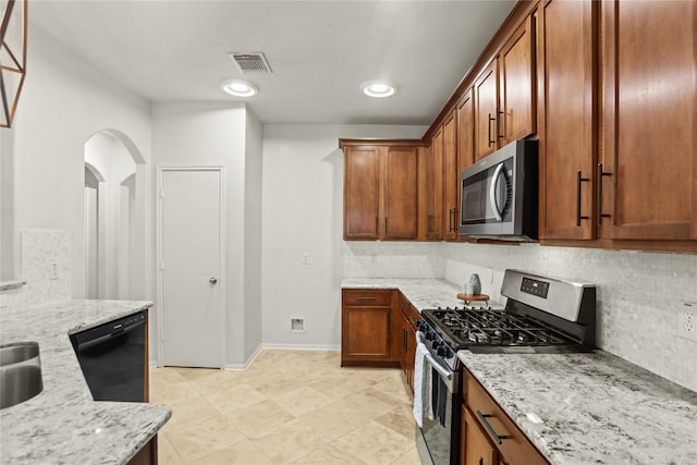 kitchen featuring tasteful backsplash, light stone countertops, sink, and stainless steel appliances