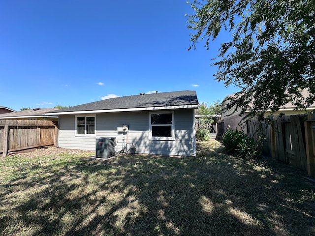 back of property with a yard and central AC