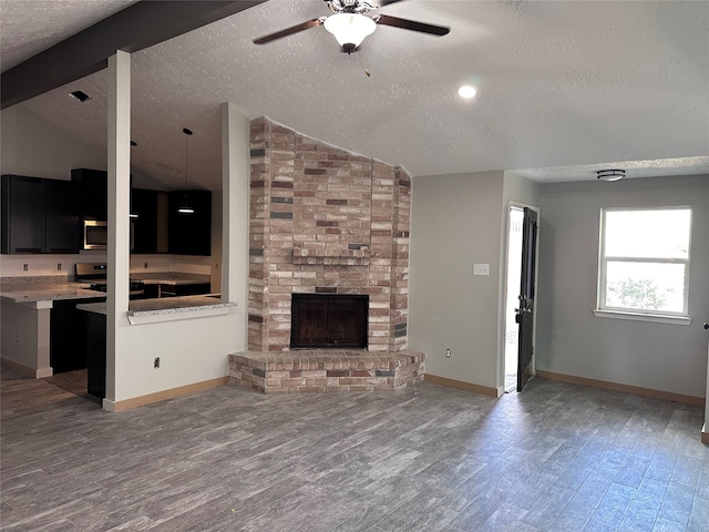 unfurnished living room featuring hardwood / wood-style floors, lofted ceiling with beams, ceiling fan, a fireplace, and a textured ceiling