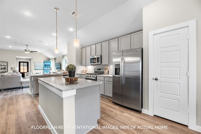 kitchen with lofted ceiling, gray cabinets, light stone countertops, light wood-type flooring, and stainless steel appliances