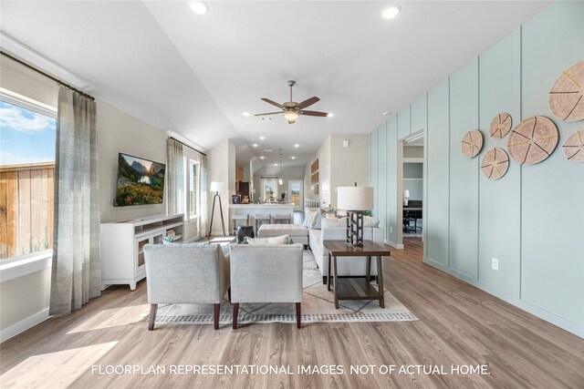 living room featuring ceiling fan, vaulted ceiling, and light hardwood / wood-style flooring