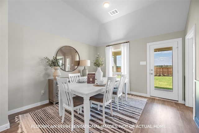 dining space with hardwood / wood-style floors and vaulted ceiling