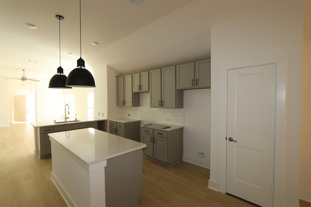 kitchen with light wood-style flooring, decorative backsplash, a sink, and gray cabinetry