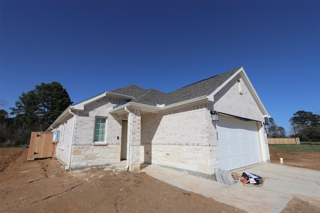 view of front of property featuring stone siding, a shingled roof, an attached garage, and brick siding