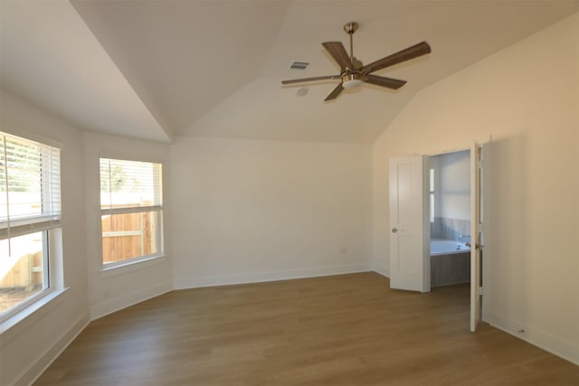 empty room featuring lofted ceiling, visible vents, baseboards, and wood finished floors