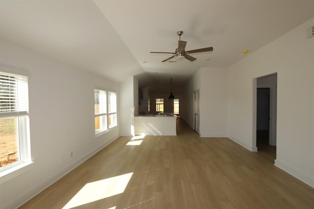 unfurnished living room featuring ceiling fan, visible vents, baseboards, vaulted ceiling, and light wood finished floors