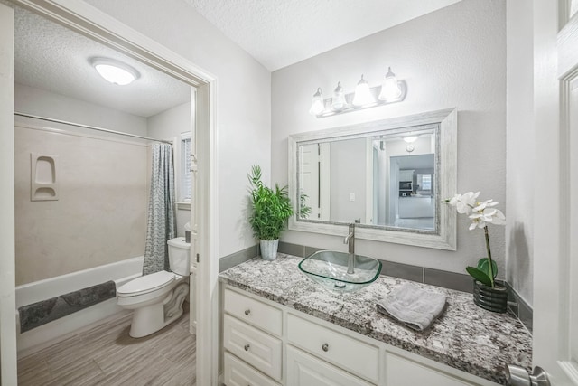 full bathroom with vanity, shower / bathtub combination with curtain, a textured ceiling, and toilet