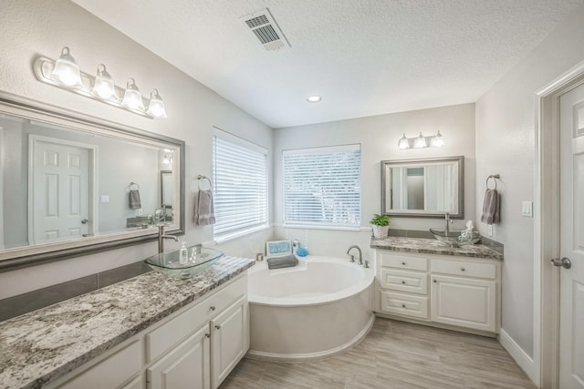 bathroom with a tub, vanity, a textured ceiling, and hardwood / wood-style flooring