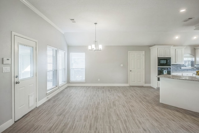 kitchen with light stone countertops, white cabinetry, light hardwood / wood-style floors, black appliances, and ornamental molding