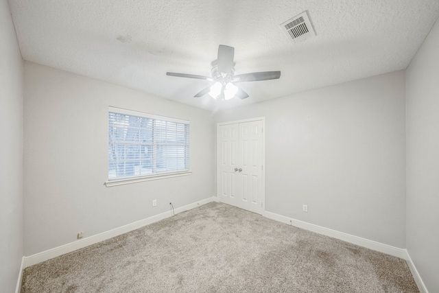 carpeted empty room with ceiling fan and a textured ceiling