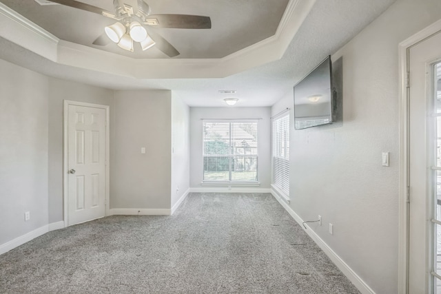 carpeted empty room featuring a raised ceiling, crown molding, and ceiling fan