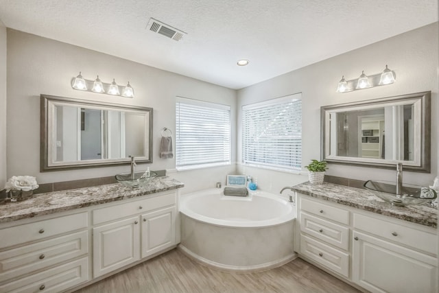 bathroom with hardwood / wood-style floors, vanity, a bathing tub, and a textured ceiling