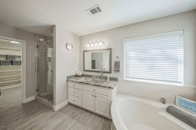 bathroom with vanity, a healthy amount of sunlight, a textured ceiling, and shower with separate bathtub