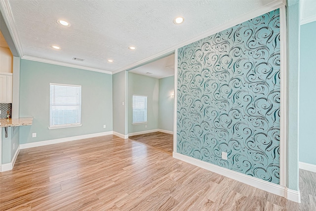 interior space featuring ornamental molding, a textured ceiling, and light hardwood / wood-style flooring