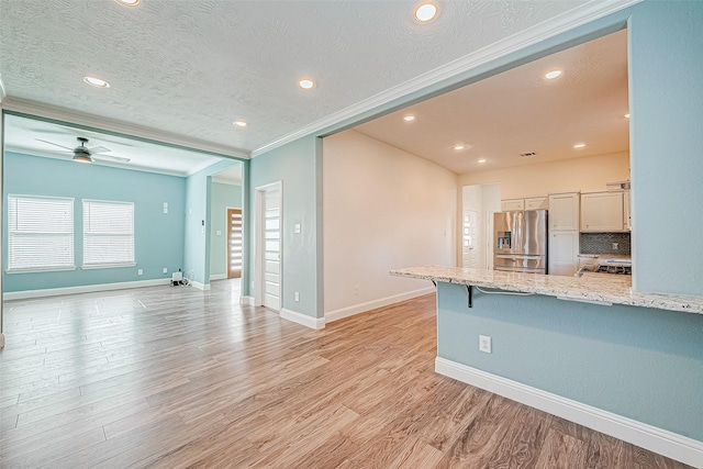 kitchen with crown molding, light hardwood / wood-style flooring, stainless steel fridge with ice dispenser, white cabinetry, and a breakfast bar area