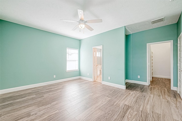 unfurnished bedroom featuring connected bathroom, ceiling fan, light hardwood / wood-style flooring, and a textured ceiling