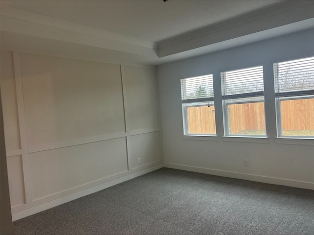 unfurnished room featuring a raised ceiling and dark colored carpet