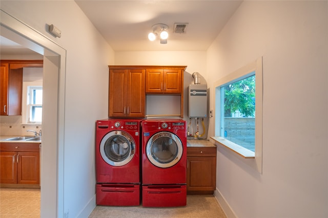 laundry room featuring washer and dryer, tankless water heater, cabinets, and sink