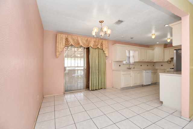 kitchen with stainless steel fridge, white dishwasher, sink, light tile patterned floors, and a notable chandelier