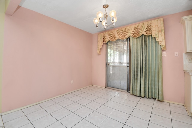 empty room with light tile patterned flooring and a notable chandelier