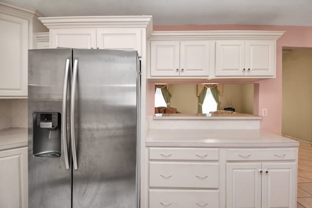 kitchen with decorative backsplash, stainless steel fridge, and white cabinetry