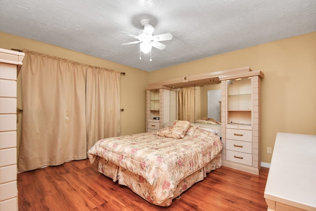 bedroom featuring dark hardwood / wood-style floors, ceiling fan, and a textured ceiling