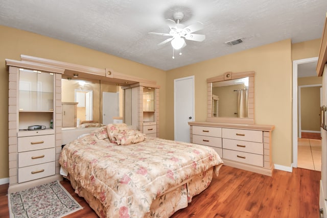 bedroom featuring ceiling fan, hardwood / wood-style floors, and a textured ceiling