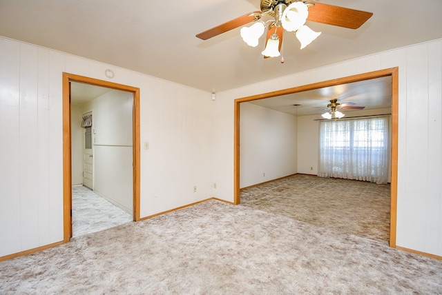 carpeted spare room with ceiling fan and wood walls