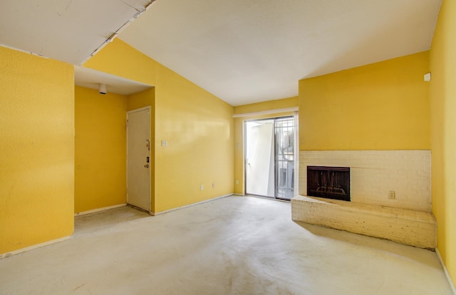 unfurnished living room featuring concrete flooring, a fireplace, and vaulted ceiling