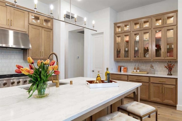 kitchen featuring tasteful backsplash, light stone counters, decorative light fixtures, and a kitchen breakfast bar