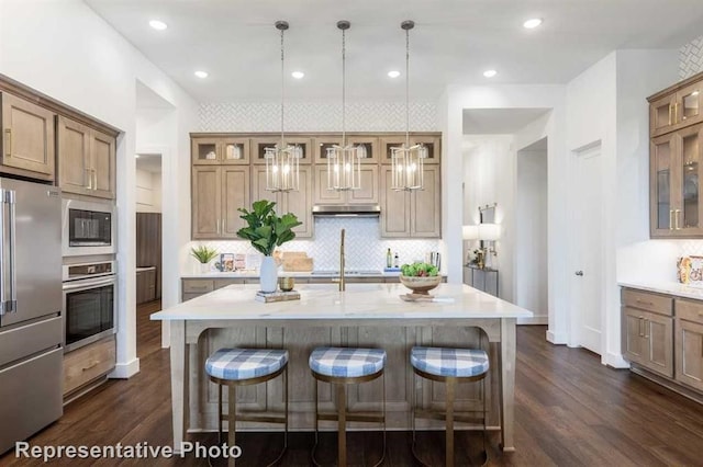 kitchen with a kitchen breakfast bar, an island with sink, hanging light fixtures, and black appliances