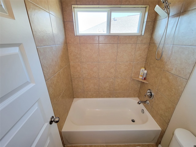 bathroom featuring toilet and tiled shower / bath