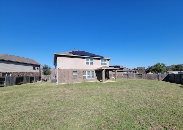 rear view of house with a lawn, solar panels, and a patio