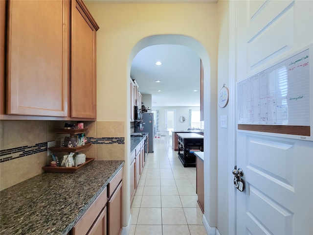 kitchen featuring decorative backsplash, dark stone countertops, and light tile patterned flooring