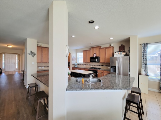 kitchen featuring a kitchen bar, kitchen peninsula, tasteful backsplash, and black appliances