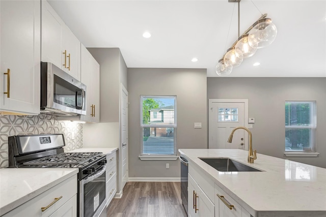 kitchen featuring light stone countertops, stainless steel appliances, sink, hardwood / wood-style flooring, and white cabinets